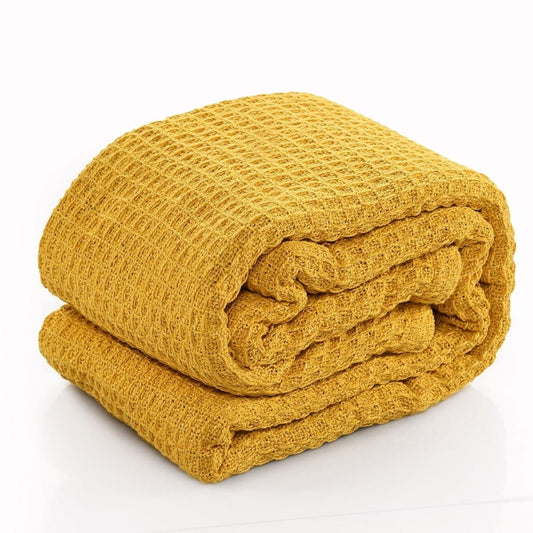 Against a white background, the throw of the Mustard Waffle Cotton Throw with Cushion Cover, a yellow throw and cover set you can buy online at Sukham Home, a sustainable furniture, kitchen & dining and home decor store in Kolkata, India