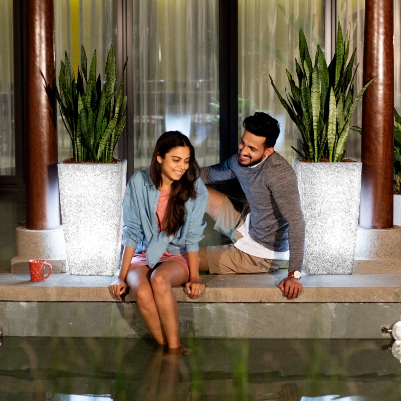 Arranged by the poolside, two Paris, a tall square stone finish plastic planter that looks like granite and comes with LED lights available at Sukham Home, a sustainable furniture, gardening and home decor store in Kolkata, India