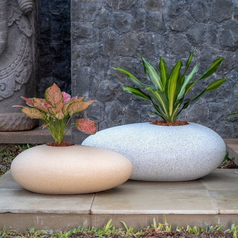 With plants inside, in Cream Stone and White Stone, the Pebble, a rock-shaped stone finish plastic planter that looks like granite available at Sukham Home, a sustainable furniture, gardening and home decor store in Kolkata, India