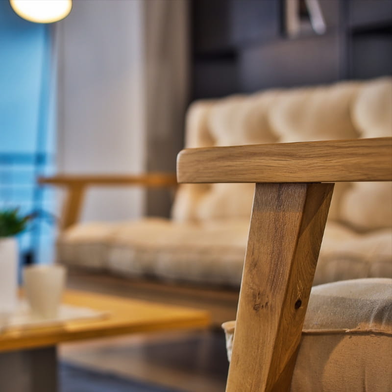 Close up of the arms of Oak Natural Poise Armchair, a wooden cushioned midcentury seat you can buy online at Sukham Home, a sustainable furniture, kitchen & dining and home decor store in Kolkata, India