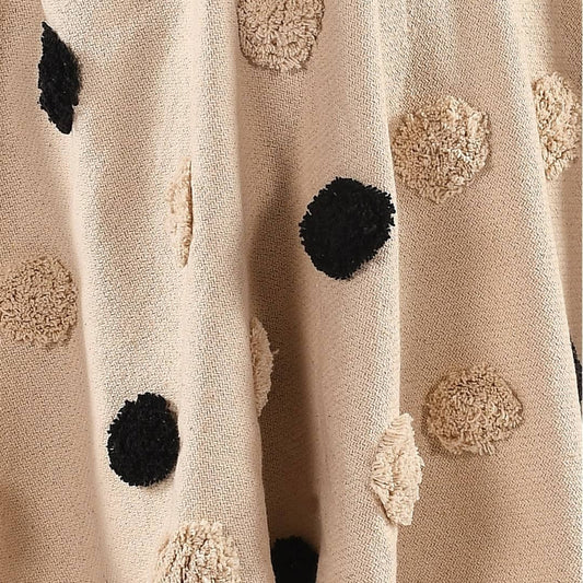 Close up of the tufted pom pom texture on the Monochromatic Polka Dot Throw, a black and white throw you can buy online at Sukham Home, a sustainable furniture, kitchen & dining and home decor store in Kolkata, India