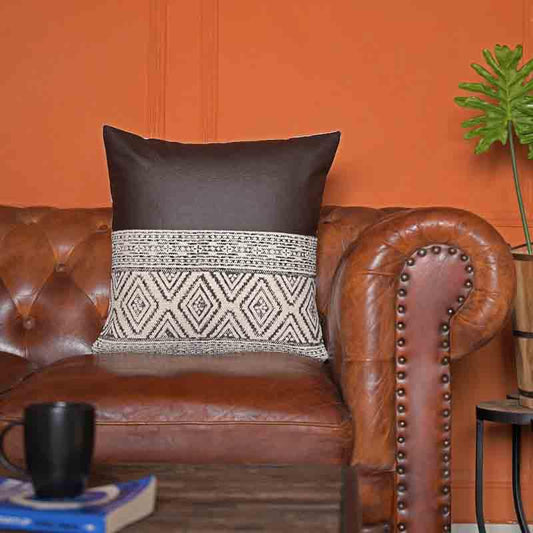 Placed on a brown tan sofa, the Querencia Cushion, a black leatherette cotton handpainted and tufted accent pillow you can buy online at Sukham Home, a sustainable furniture, kitchen & dining and home decor store in Kolkata, India