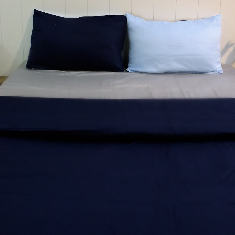 One navy blue pillow cover and one sky blue pillow cover with navy blue duvet of the Navy Blue-Sky Blue Reversible Egyptian Cotton Duvet Cover, a dual king size duvet cover you can buy online at Sukham Home, a sustainable furniture, gardening and home decor store in Kolkata, India