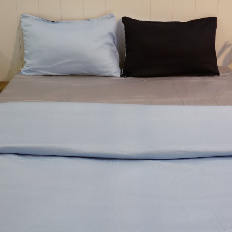 One navy blue and one sky blue pillow cover with the sky blue duvet cover side of the Navy Blue-Sky Blue Reversible Egyptian Cotton Duvet Cover, a dual king size duvet cover you can buy online at Sukham Home, a sustainable furniture, gardening and home decor store in Kolkata, India