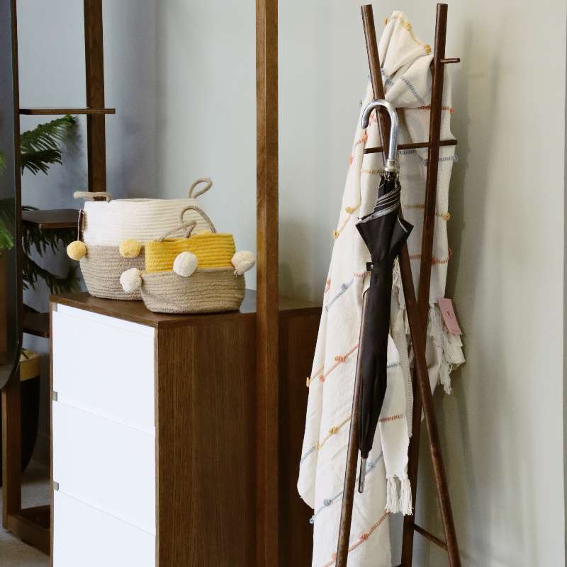 With an umbrella and throw placed on it, the Oak Antique Scarecrow, a wooden entryway designer quirky coat hanger you can buy online at Sukham Home, a sustainable furniture, kitchen & dining and home decor store in Kolkata, India