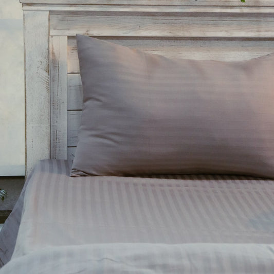 A pillowcase and sheet of the Grey Sateen Striped Bedsheet, a king size cotton bedsheet you can buy online at Sukham Home, a sustainable furniture, gardening and home decor store in Kolkata, India