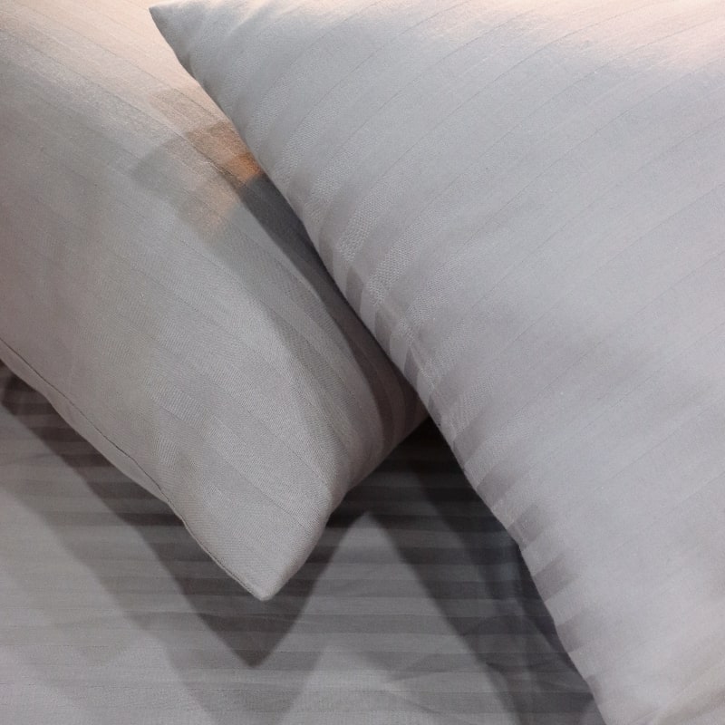 Close up of the pillowcases of the Grey Sateen Striped Bedsheet, a king and queen size cotton bedsheet you can buy online at Sukham Home, a sustainable furniture, gardening and home decor store in Kolkata, India