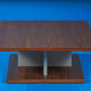 Against a blue background, the Walnut Natural Stage Centre Table, a wooden square coffee and centre table you can buy online at Sukham Home, a sustainable furniture, kitchen & dining and home decor store in Kolkata, India