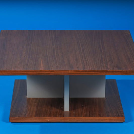 Against a blue background, the Walnut Natural Stage Centre Table, a wooden square coffee and centre table you can buy online at Sukham Home, a sustainable furniture, kitchen & dining and home decor store in Kolkata, India