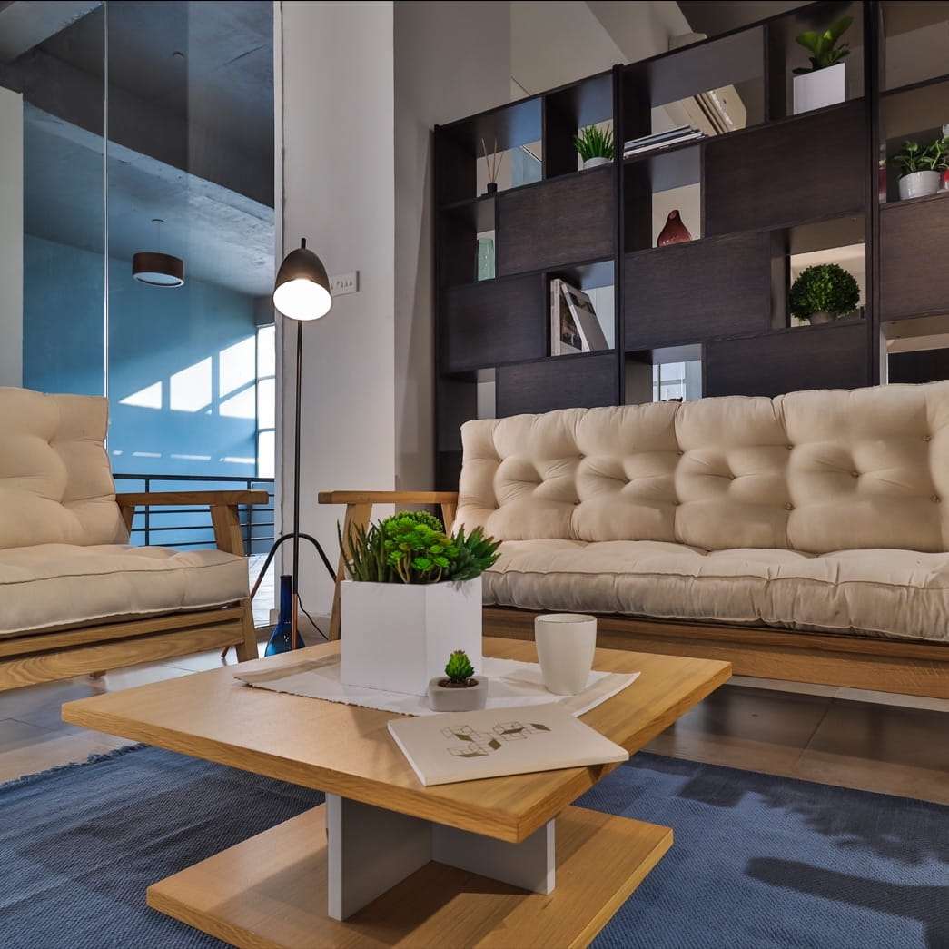 Corner view of the living room set up with the sofas and the Stage Centre Table, a wooden square coffee and centre table you can buy online at Sukham Home, a sustainable furniture, kitchen & dining and home decor store in Kolkata, India