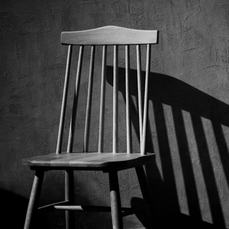 In a black and white filter, the String Chair, a solid wood Windsor dining seat you can buy online at Sukham Home, a sustainable furniture and home decor store in Kolkata, India