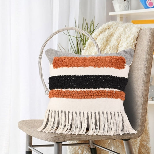 Arranged on a chair, the Tasselled & Tufted Cushion, a square white and orange accent pillow available at Sukham Home, a sustainable furniture, kitchen & dining and home decor store in Kolkata, India