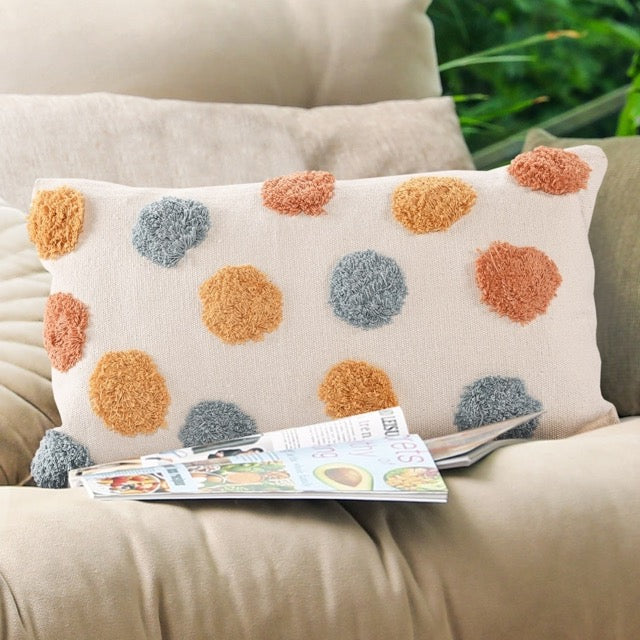 On a beige-grey sofa, the Tufted Multicolour Dot Cushion, a rectangle orange, blue, white and yellow accent pillow available at Sukham Home, a sustainable furniture, kitchen & dining and home decor store in Kolkata, India