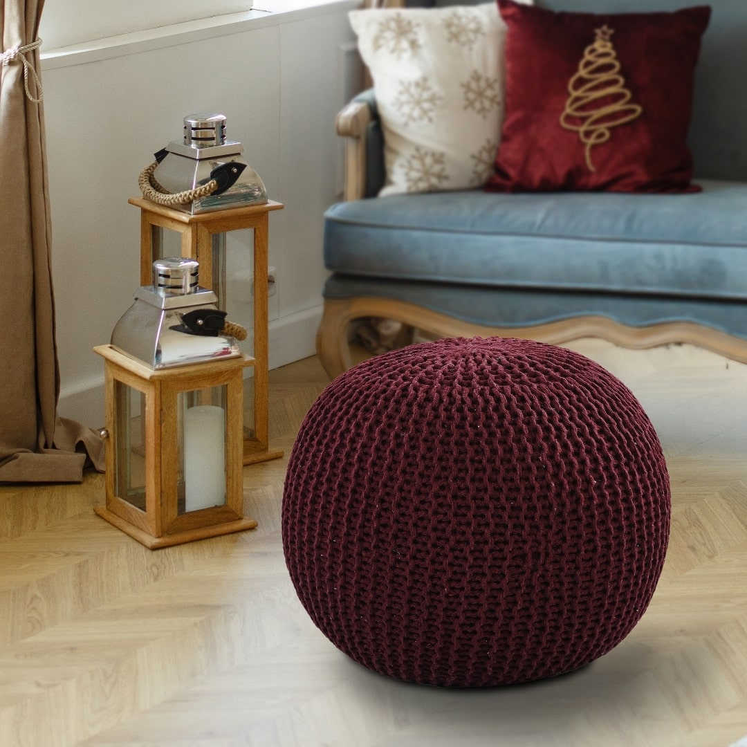 Placed on a wood floor, the Wine Knitted Pouf, a red magenta ottoman made from cotton, available at Sukham Home, a sustainable furniture, kitchen & dining and home decor store in Kolkata, India