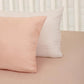 Against a white pillow, the Pink Solid Bedsheet, a pale pink king and queen size cotton bedsheet you can buy online at Sukham Home, a sustainable furniture, gardening and home decor store in Kolkata, India